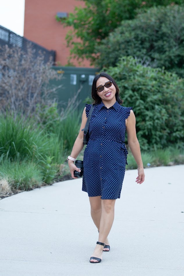 Nga Vu, smiling and walking outdoors in a navy polka-dot dress